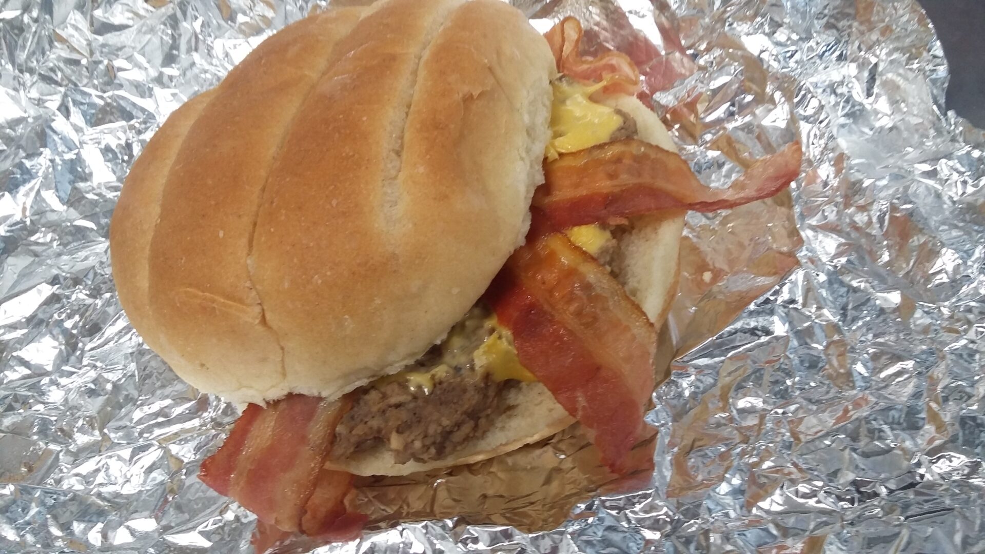 A closeup shot of a burger in tin foil