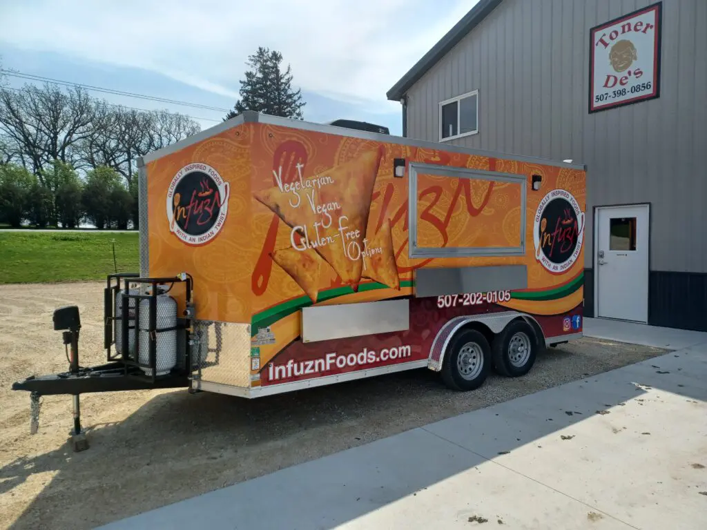 A Orange food trailer parked outside a warehouse