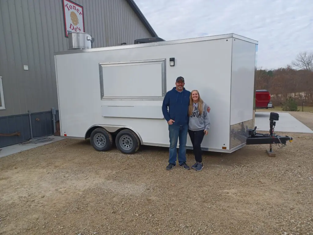 A couple standing in front of a trailer in front of a warehouse.